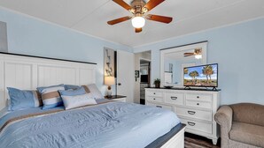 A bedroom with a bed, a dresser, a chair, a ceiling fan, and a television. - 3 BEDROOM BEACH HOUSE WITH GOLF CART! (Myrtle Beach)