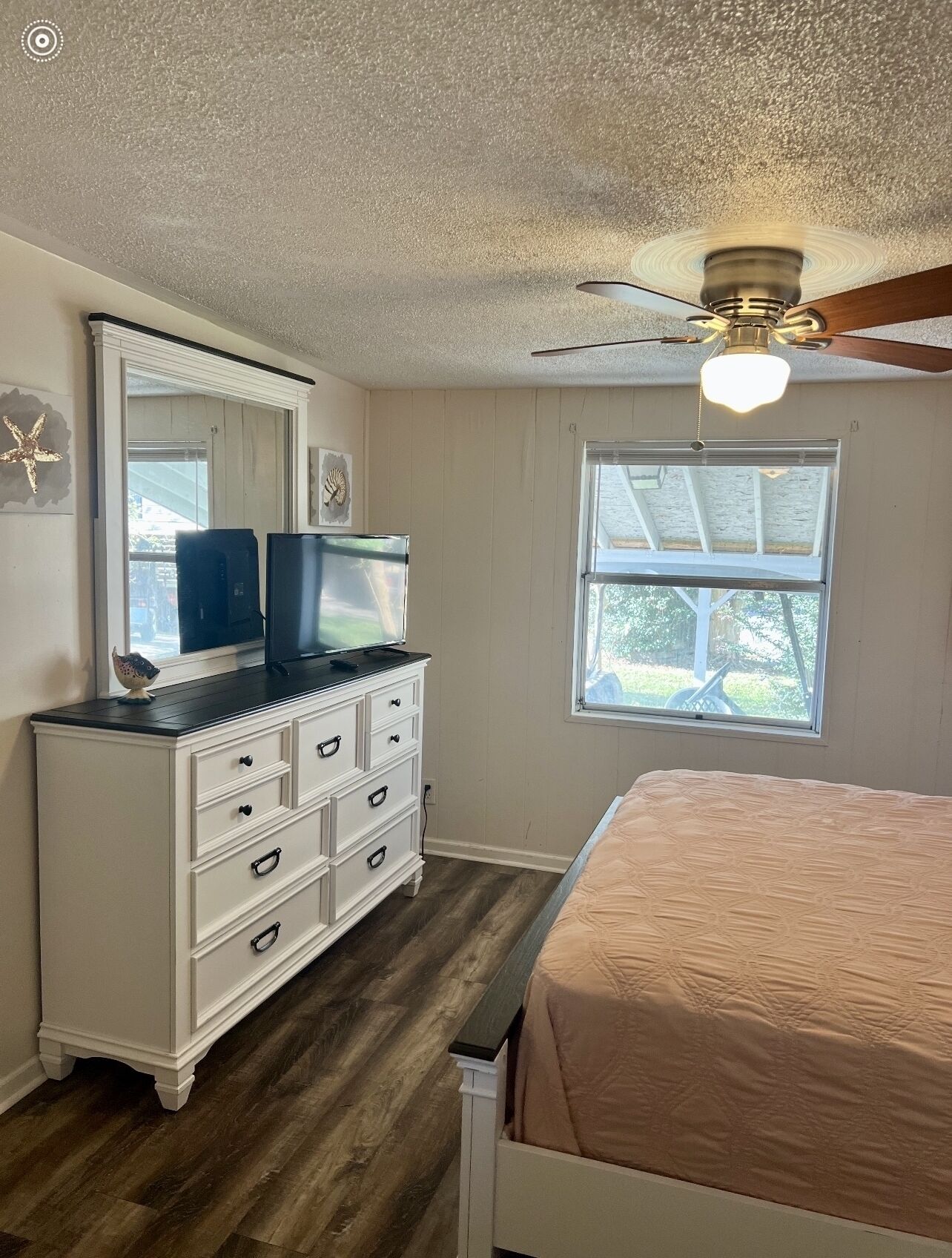 Un dormitorio con cama, cómoda y ventilador de techo.