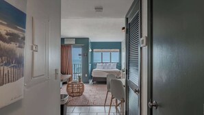 A hotel room with a bed, a chair, a small table, a wicker chair, a view of the sea, and a door leading to a balcony. - Nicely Updated!  Oceanfront Studio - Palace 302 (Myrtle Beach)