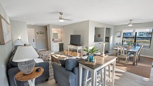Ett modernt vardagsrum med en soffa, ett soffbord, en tv och en matplats med stolar och ett bord.