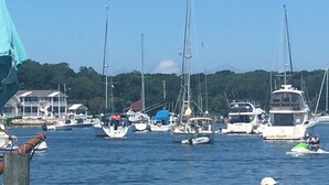 Een jachthaven met verschillende boten afgemeerd, een heldere lucht en een bebost heuvel op de achtergrond.