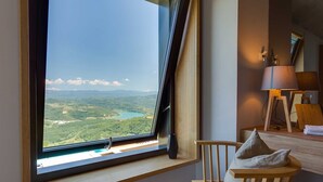 A room with a large window overlooking a landscape, a wooden chair, a lamp, and a bedside table. - Villa Grand Horizon with Pool (Pazin)