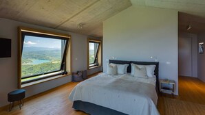 A bedroom with a large bed, two windows with views of a lake and mountains, and a wooden ceiling. - Villa Grand Horizon with Pool (Pazin)