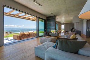 En rummelig opholdsstue med en stor skydedør, der fører ud til en balkon med udsigt over et smukt landskab.