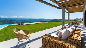 A covered outdoor area with a pool, lounge chairs, and a view of the landscape. - Villa Grand Horizon with Pool (Pazin)