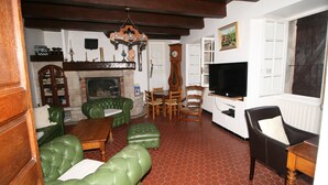 Un salón tradicional con sofás de cuero verde, chimenea, muebles de madera y televisor.