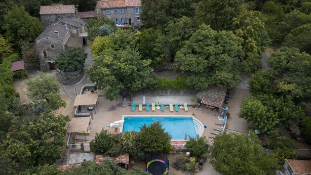 Vista aérea de una zona residencial con piscina, sillas de descanso y un trampolín.