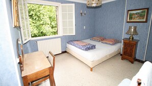 Un dormitorio con cama, ventana, mesa y lámpara.