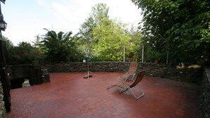 Un patio con piso de ladrillo, pared de piedra y una silla de madera.