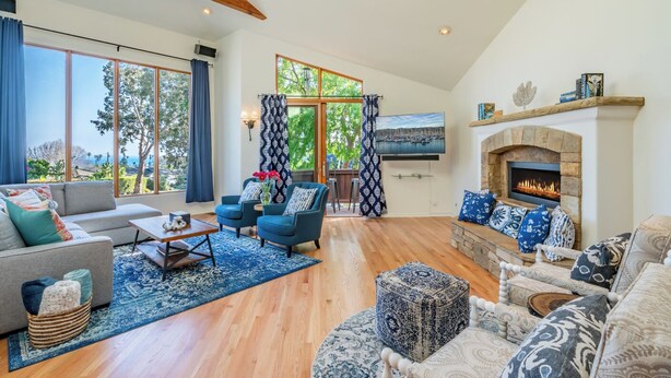 A spacious living room with a fireplace, large windows, and a cozy seating area. - Large Home with Ocean Views & Hot Tub! (Santa Barbara)