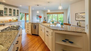 A modern kitchen with granite countertops, white cabinetry, and a stainless steel range hood. - Large Home with Ocean Views & Hot Tub! (Santa Barbara)