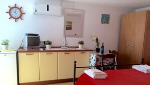Une chambre à coucher avec un lit, un bureau avec un ordinateur, une armoire et une petite table avec une plante.