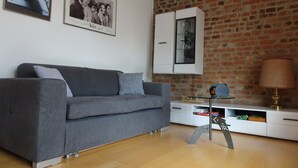 A living room with a grey sofa, a white cabinet with a glass door, and a brick wall. - Country house style meets modernity (Mühlheim am Main)