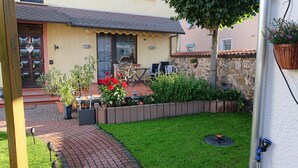 A house with a tiled roof, a brick pathway leading to the entrance, and a small garden area with potted plants and a lawn. - Country house style meets modernity (Mühlheim am Main)