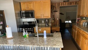 A modern kitchen with wooden cabinets, stainless steel appliances, and a granite countertop.