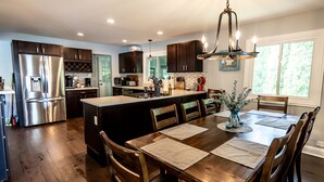 A modern kitchen with dark wood cabinets, stainless steel appliances, and a central island with seating. - Pet Friendly Huge Lake Front Home with Stunning Views (Round Lake Park)