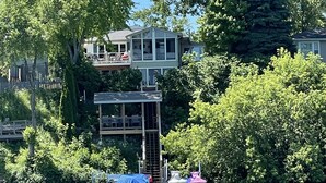 A lakeside property with a dock, a covered boat launch, and a house with a balcony overlooking the water. - Pet Friendly Huge Lake Front Home with Stunning Views (Round Lake Park)