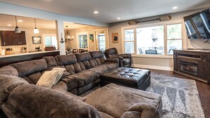 A modern living room with a sectional sofa, a fireplace, and a large window. - Pet Friendly Huge Lake Front Home with Stunning Views (Round Lake Park)