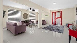 Un salón amplio con diseño moderno, que incluye un gran sofá, una mesa de centro y una puerta con marco rojo.