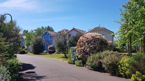 Una calle residencial con casas, cielo despejado y jardines cuidados.