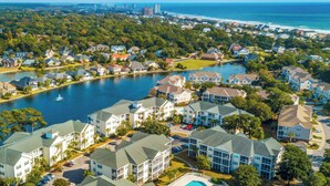 Un quartiere residenziale con case lungo un lago, una spiaggia e uno skyline urbano sullo sfondo.