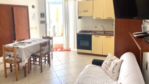 A compact living space with a dining area, kitchenette, and a sofa. - Conti Holiday Homes - Begonia (Ponza)