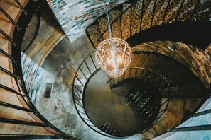 Escadaria em espiral com um lustre decorativo no topo.