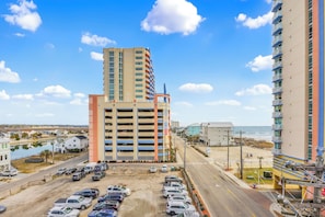 A multi-story hotel with a parking lot, a beach view, and a road leading to the beach.