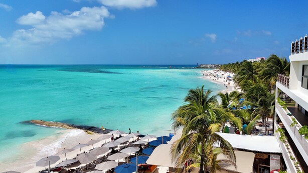 Un resort frente al mar, con sombrillas de playa y palmeras.