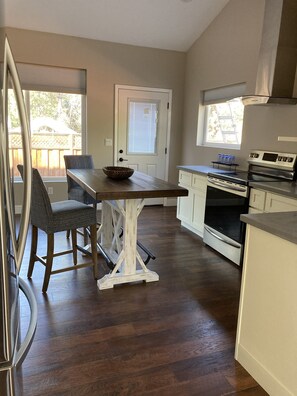 A modern kitchen with a dining area, wooden flooring, and a view of the backyard through a door. - Charming Private Guest House - Alamo (Alamo)