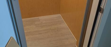 An elevator with a wooden wall and a metallic floor.