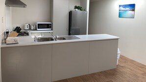 A modern kitchen with a central island, stainless steel appliances, and a view of the sea through the window. - Skylight Retreat Falcon (Falcon)
