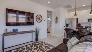 A modern living room with a large TV, a wooden console table, and a patterned rug. - Modern | Clean | Getaway for Two! Mini Ranch Casita (Washington)