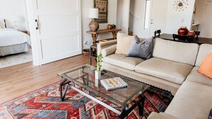 Un salon avec un canapé, une table basse en verre, un tapis et une porte.