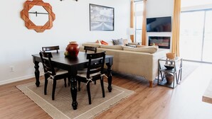 Un salon moderne comprenant un coin repas, un canapé, un téléviseur et une cheminée.
