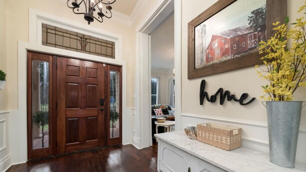 A wooden front door with glass panels, a white console table with baskets, and a 'home' sign on the wall. - 1920's Sunny Gem - Downtown Waco Home (Waco)