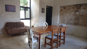 A dining area with a wooden table and chairs, a brown sofa, and a patterned rug.