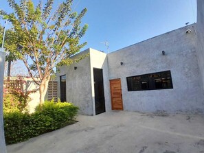 A modern building with a concrete facade, a wooden door, and a window with a grid pattern. - industrial local style 10 min to downtown swimming pool and garage.  (Mérida)