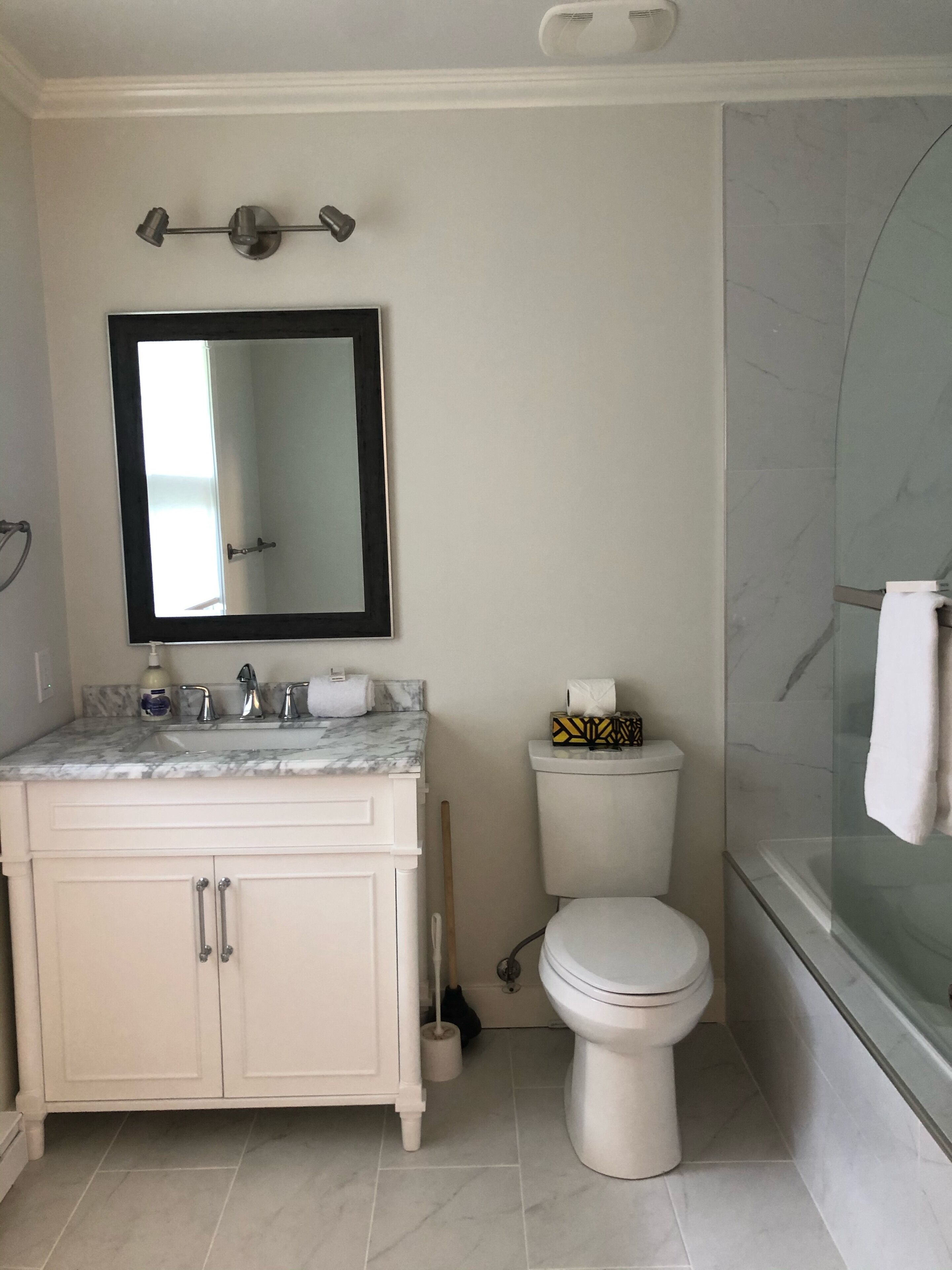 A bathroom with a marble sink, a toilet, and a glass shower enclosure.