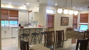 A modern kitchen with a central island, bar stools, and a dining table with chairs.
