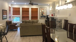 A living room with a sofa, chairs, a dining table, and a ceiling fan.