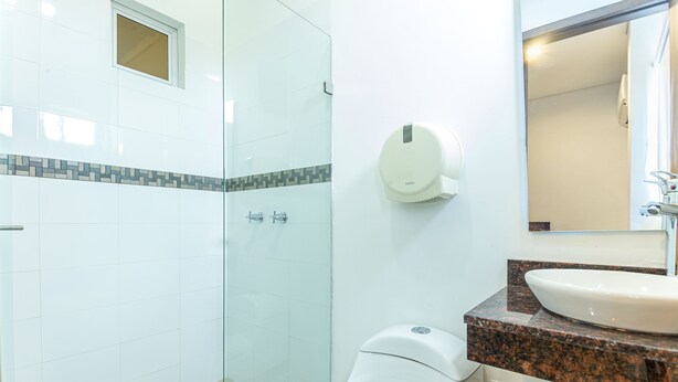 Une salle de bain avec une douche à parois de verre, des toilettes blanches, un comptoir en marbre et un lavabo.