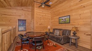 Cozy cabin-style space with a round dining table, leather chairs, and a dark sofa.