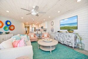 A spacious living room with a round coffee table, a sofa, and a TV mounted on the wall.