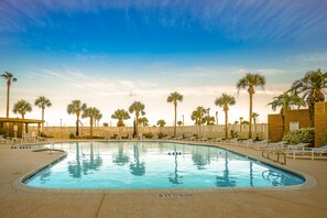 A pool area with lounge chairs and palm trees.