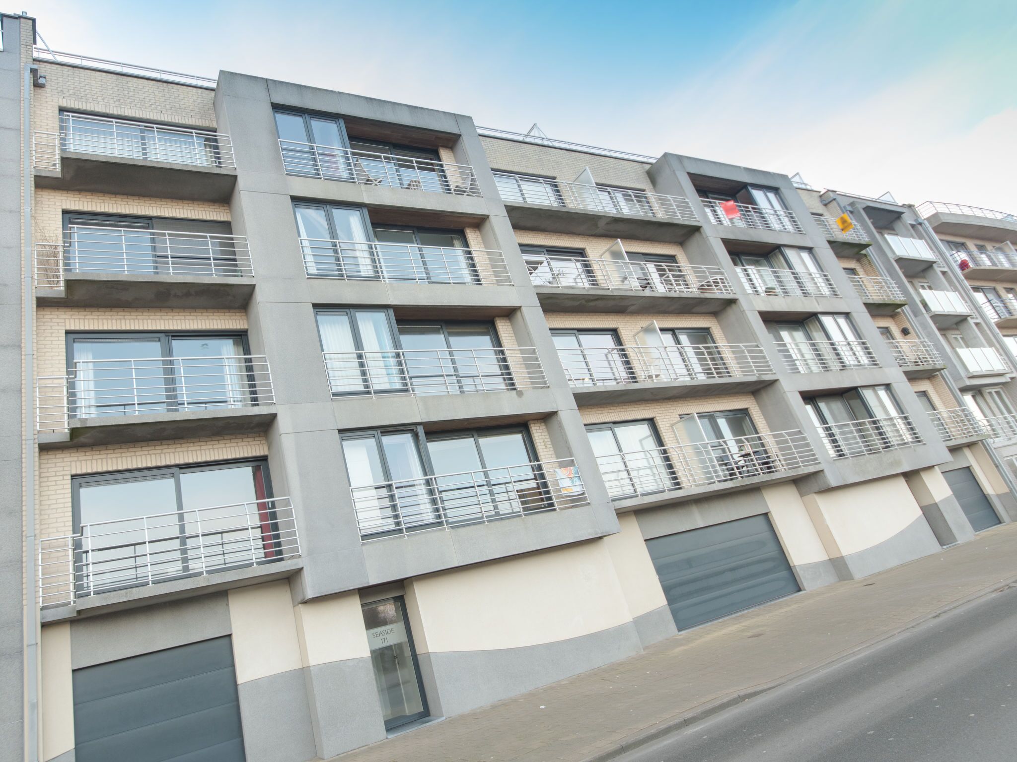 A multi-story residential building with balconies, large windows, and a flat facade.