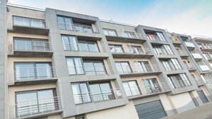 A multi-story residential building with balconies, large windows, and a flat facade.