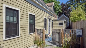 En bostadsbyggnad med en grind vid ingången, en liten veranda och en skylt som visar att parkering endast är tillåten för gäster och boende.