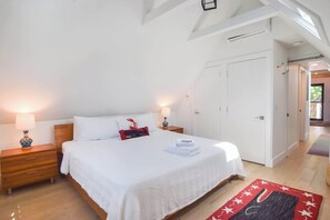 Une chambre à coucher comprenant un lit, des tables de chevet, une lampe, une armoire et une vue sur l’extérieur.