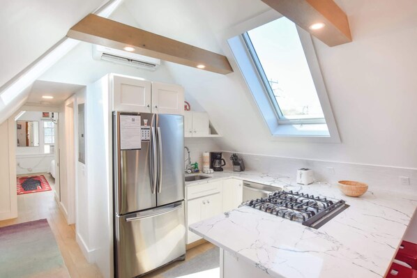 Une cuisine moderne équipée d’un réfrigérateur en acier inoxydable, d’une cuisinière à gaz et d’une lucarne.